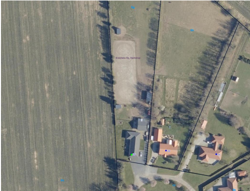 Oversigtsfoto, der viser placeringen af ridebanen på ejendommen. Ridebanen er placeret nord for bebyggelse og ud for marker.