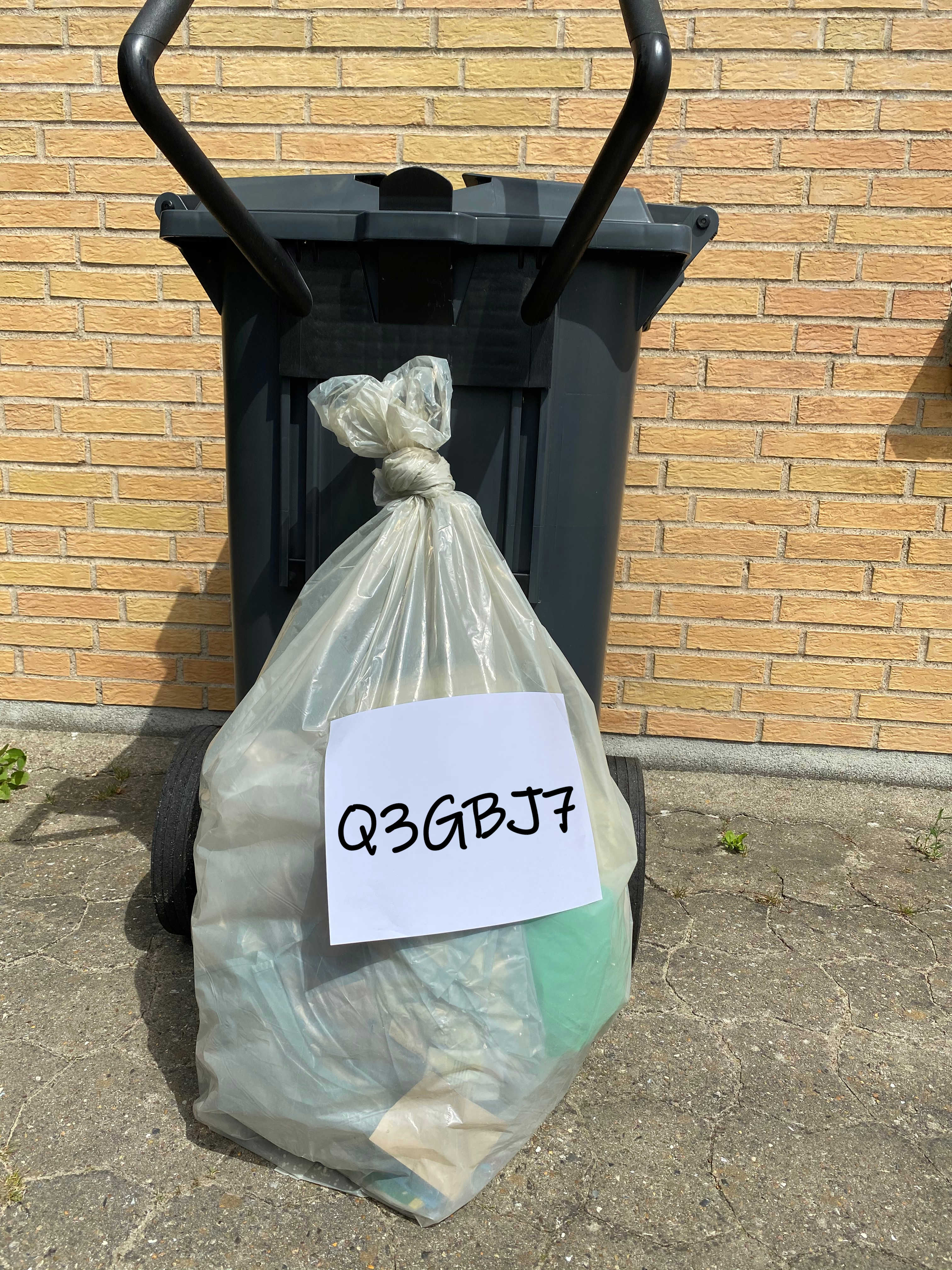 En ekstrasæk står ved kantstenen sammen med en skraldespand